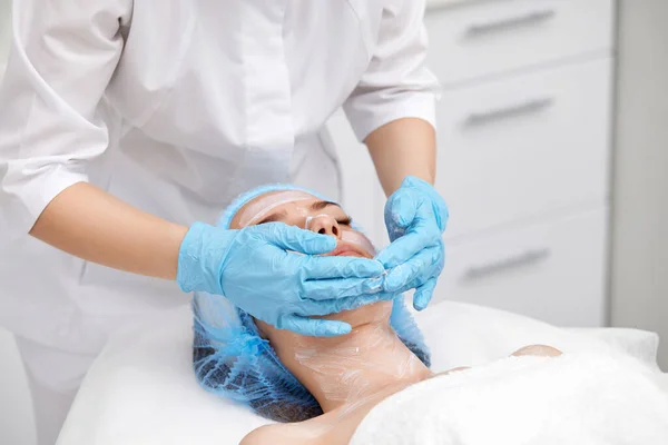 Kosmetolog Applicerar Masken Ansiktet Vacker Ung Kvinna Spasalongen Ansiktsbehandling Hudvård — Stockfoto