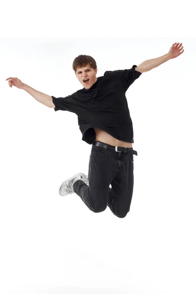 Возбужденный Молодой Человек Черной Футболке Улыбается Прыгая Воздухе Белом Фоне — стоковое фото