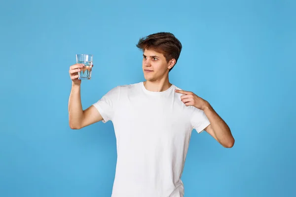 Νεαρός Όμορφος Άντρας Που Δείχνει Ένα Ποτήρι Νερό Μπλε Φόντο — Φωτογραφία Αρχείου