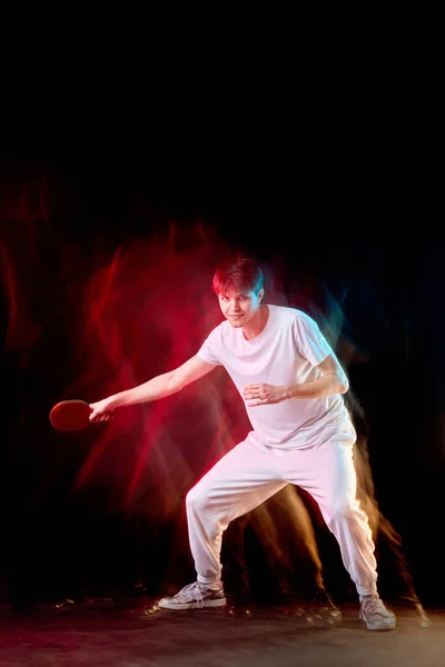 濃い背景のネオンで卓球をしているスポーツマン 動きの概念 — ストック写真