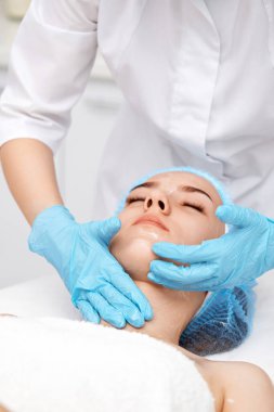 Genç ve güzel bir kadın güzellik salonunda yüz masajı yaptırıyor.