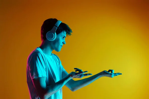 Young Man Listening Music Headphones Yellow Background Neon Lighting — Stock Photo, Image