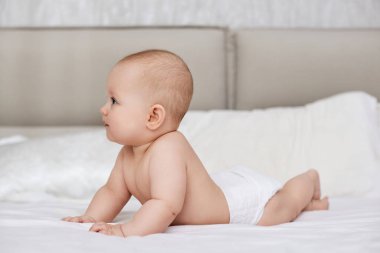 Evdeki beyaz çarşafların üzerinde yatan yeni doğmuş tatlı bir kız bebek.