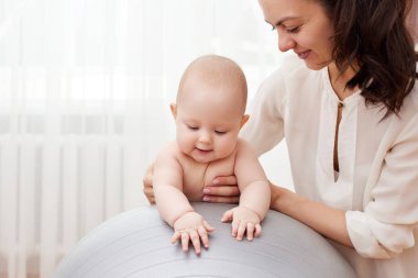 Mutlu anne evde bir fitness topunda küçük kızıyla oynuyor.