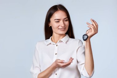 Gülümseyen esmer kadın arabanın anahtarlarını gri arka planda tutuyor. Yeni bir araba almak. Boşluğu kopyala