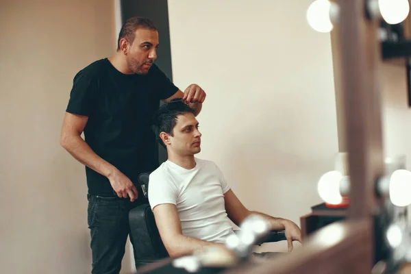 Professional hairdresser and caucasian man in front of the mirror in barber shop