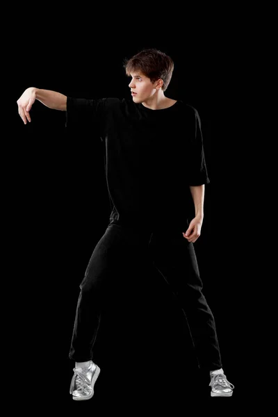 黒のTシャツに身を包んだ若者が黒を背景に踊っている — ストック写真