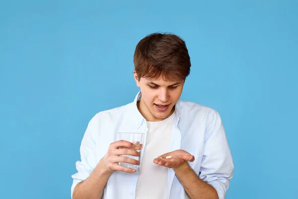 Junger Mann Nimmt Pille Auf Blauem Hintergrund Gesundheitsversorgung Behandlungskonzept — Stockfoto
