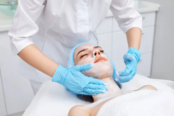 Kosmetolog Applicerar Masken Ansiktet Vacker Ung Kvinna Spasalongen Ansiktsbehandling Hudvård — Stockfoto