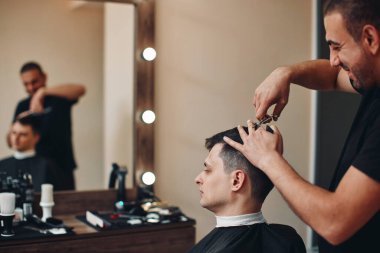 Kuaför berber dükkanında yakışıklı sakallı adama servis yapıyor..