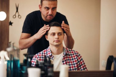 Berber dükkanında aynanın önünde sakallı ve tatmin olmuş bir adam.