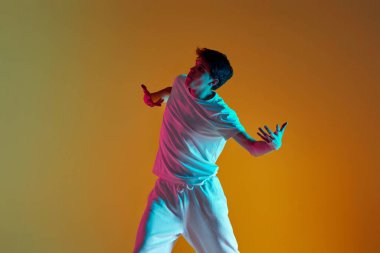 Yakışıklı adam neon ışıkta sarı arka planda neşe içinde hareket ediyor.