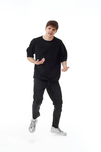 黒のTシャツとジーンズを着た若者が白い背景で踊っている — ストック写真