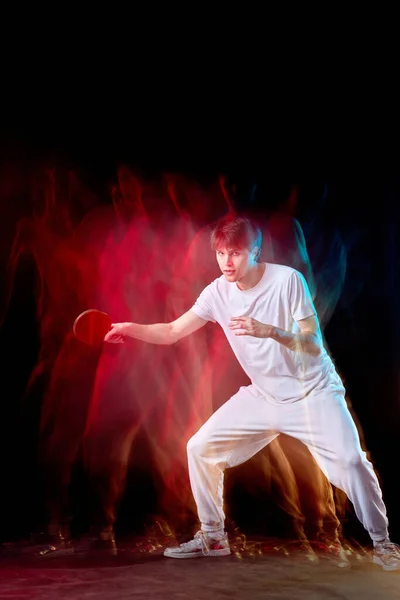 濃い背景のネオンで卓球をしてる若い男 動きの概念 — ストック写真