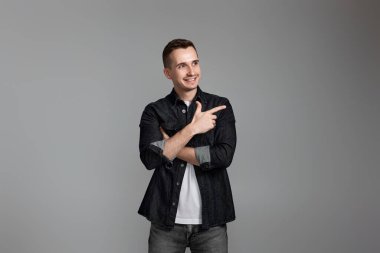 Yandaki fotokopi alanını gösteren yakışıklı genç adam gri arka planda izole edilmiş.