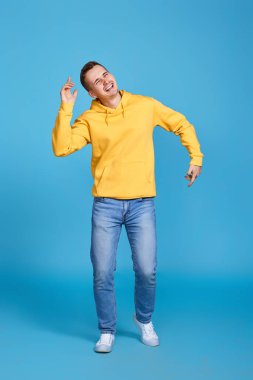 Genç yakışıklı adam mavi arka planda dans ediyor. Tüm vücut