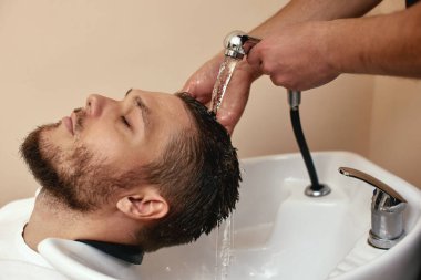 Berber dükkanında beyaz adamın saçını yıkayan berber.