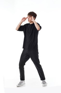 Siyah tişörtlü genç adam ve beyaz arka planda dans eden kot pantolon. Tam uzunluk