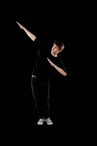young man in black t-shirt dancing on black background. Full length