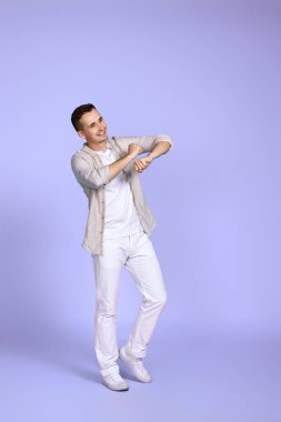 Pastel menekşe arka planda dans eden neşeli genç yakışıklı adam. Tatil yazı. Tüm vücut