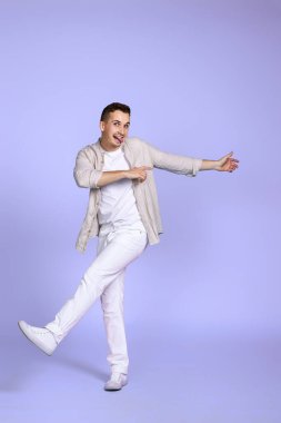 Yakışıklı, mutlu adam menekşe arka planda tek başına yürüyor..