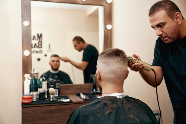 Berber berber dükkanında sakallı yakışıklı adamı tıraş ediyor..