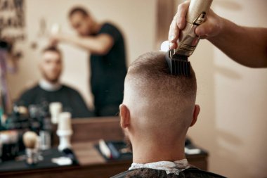 Kuaförün arka görünüşü makas ve tarakla saç stili yapıyor..