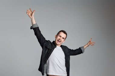 Gri arka planda izole edilmiş, başarılı bir jestle başarısını kutlayan genç adam..