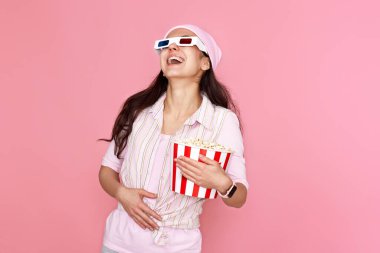 Gülen kadın pembe arka planda izole edilmiş patlamış mısır dolu bir kova tutuyor.