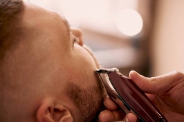 Berber berber dükkanında sakallı yakışıklı adamı tıraş ediyor..