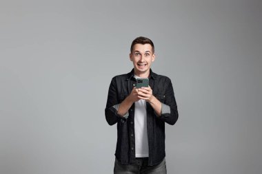 Cep telefonuyla mesajlaşan tişörtlü mutlu adam.