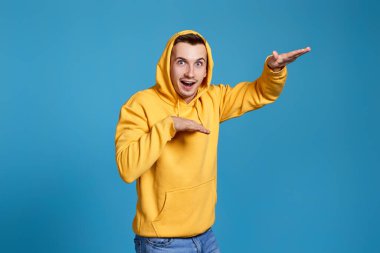 Mavi arka planda dans eden sarı tişörtlü komik adam.