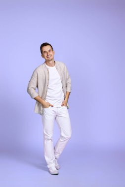 Makyaj mor arka planda poz veren rahat gömlekli yakışıklı, iyimser beyaz adam. Tam boy fotoğraf