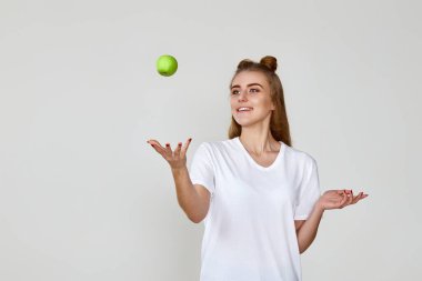 Stüdyonun arka planında yeşil elma tutan gülümseyen güzel kız. Boşluğu kopyala
