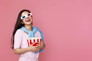 Mutlu bir kadın pembe arka planda izole edilmiş patlamış mısır kovası tutuyor.