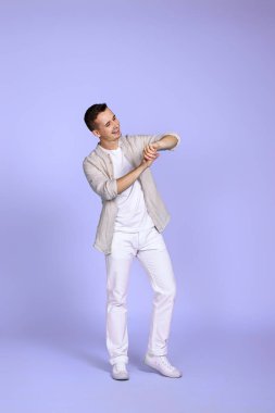Pastel mor arka planda poz veren rahat gömlekli yakışıklı bir adam. Tam boy fotoğraf