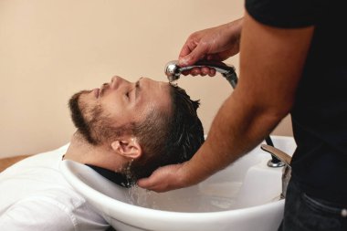 Berber dükkanında beyaz adamın saçını yıkayan berber.