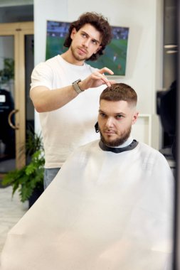 Kuaför berber dükkanında yakışıklı sakallı adama servis yapıyor..