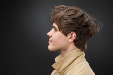 side view of caucasian man with hairstyle in coat on black background. fashion modern style look