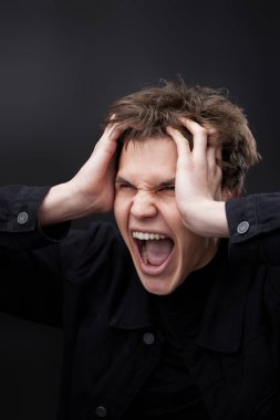 Öfkeli kızgın adam siyah stüdyonun arka planında öfkeli bir jest yapıyor.