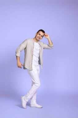 Pastel menekşe arka planda dans eden neşeli genç yakışıklı adam. Tatil yazı. Tüm vücut