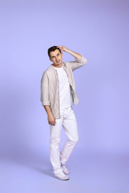 thoughtful young handsome man thinking on purple background. Full length