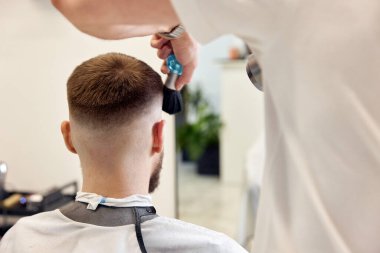 Kuaför berber dükkanında yakışıklı sakallı adama servis yapıyor..