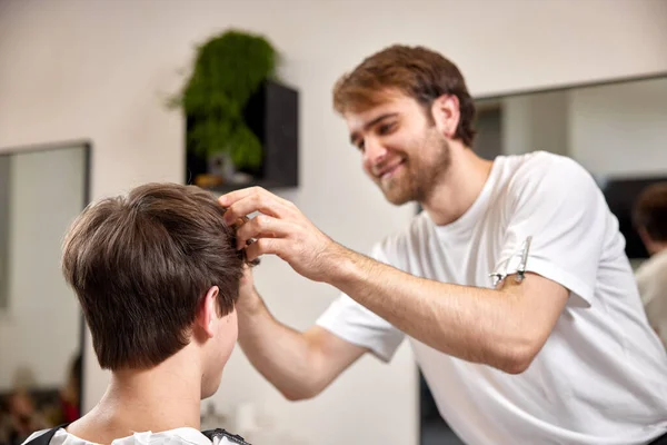 caucasian client man getting hairstyle by professional male hairstylist at barber shop.