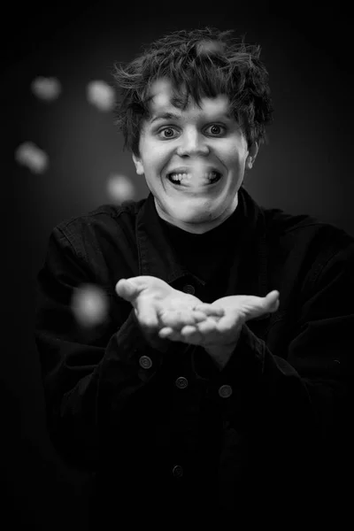 portrait of crazy young man throwing up popcorn and grimacing . black and white