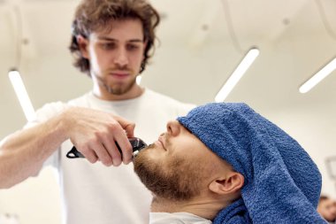 Berber berber dükkanında sakallı yakışıklı adamı tıraş ediyor..