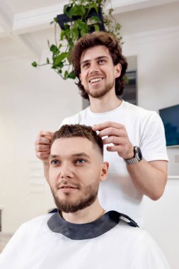 Berber dükkanında aynanın önünde sakallı ve tatmin olmuş bir adam.