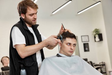 Berber berber dükkanında yakışıklı beyaz adamı tıraş ediyor..