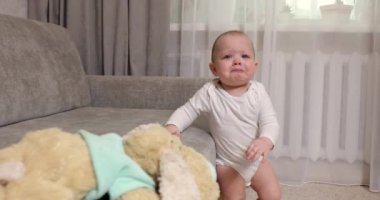 Beyaz elbiseli küçük bir kız bebek odada ağlıyor.