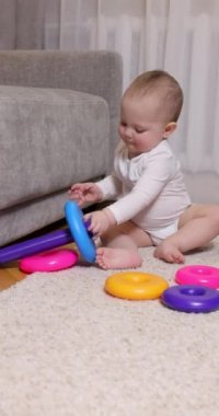 Evdeki halının üzerinde renkli oyuncak piramidiyle oynayan tatlı bir bebek. Çocuklar için erken gelişme.